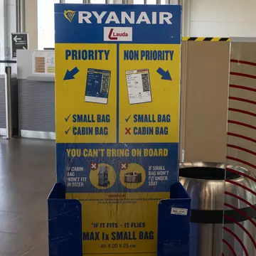 A Ryanair cabin baggage measurement cage at an empty boarding gate in an airport.