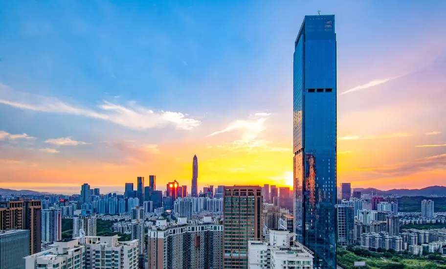 Shenzhen skyline, China, at sunset with the Ping An Finance Centre spire on the horizon and a glass tower in the foreground