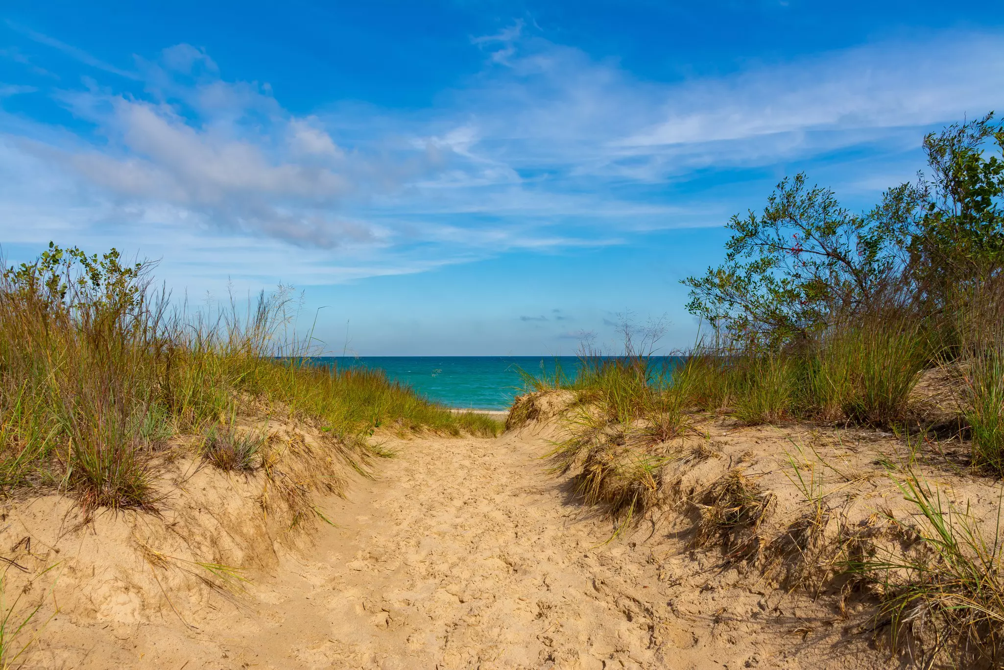 A sandy beach leading to a lakeside beach