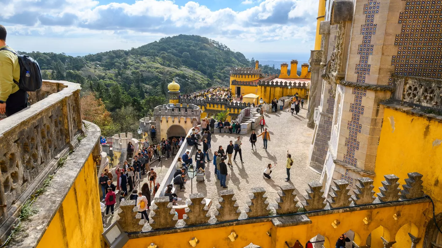 Sintra, Portugal - November 17 2023: Tourists crowd the colorful levels and platforms at the National Palace of Pena, a Romanticist castle in São Pedro de Penaferrim, in the mountains of Sintra.