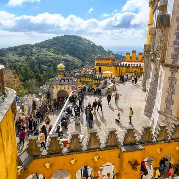 Sintra, Portugal - November 17 2023: Tourists crowd the colorful levels and platforms at the National Palace of Pena, a Romanticist castle in São Pedro de Penaferrim, in the mountains of Sintra.
