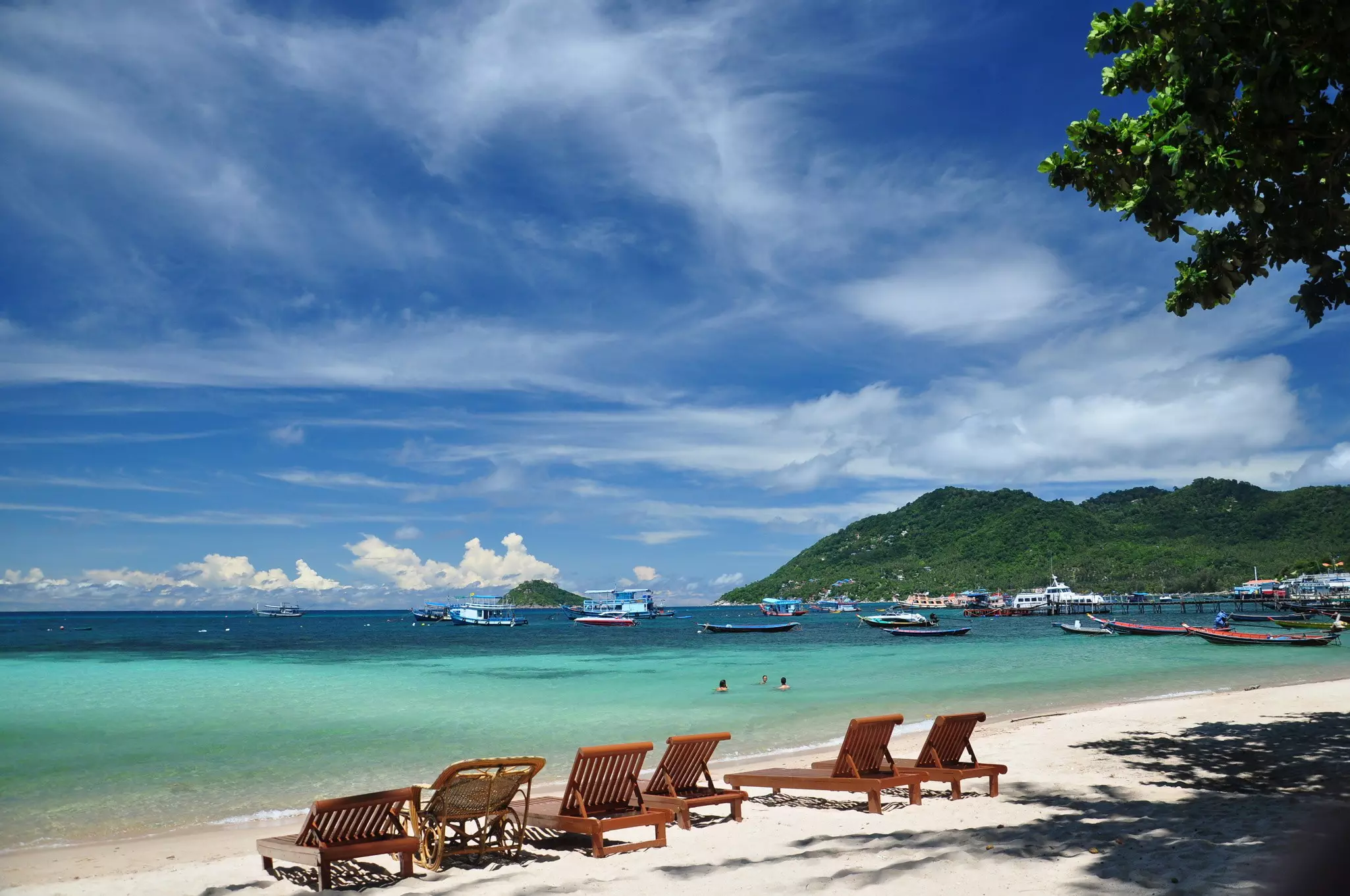 People float in the ocean off a beach near a pontoon.
