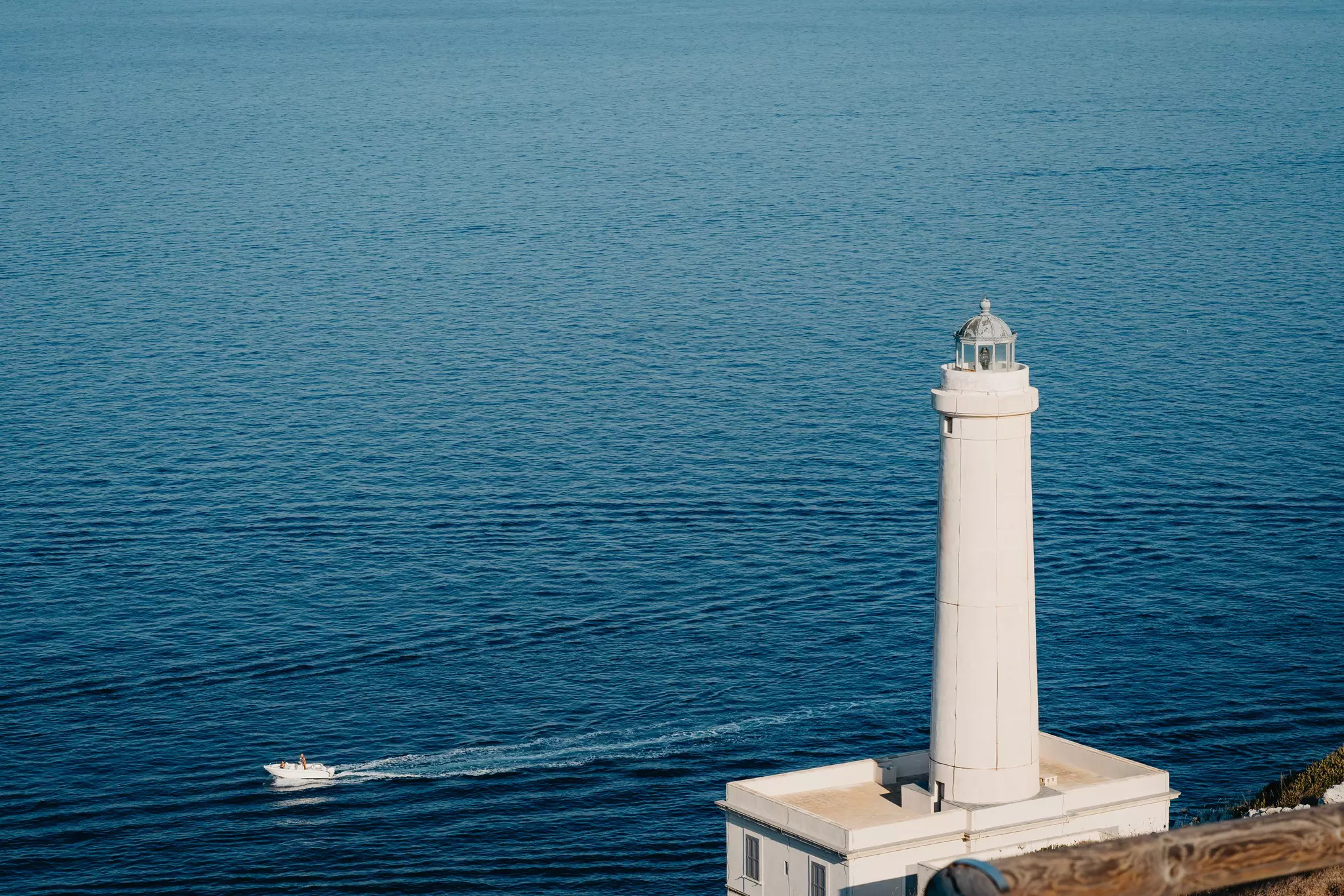 The lighthouse of Punta Palascia in Otranto, with a boat in the water nearby