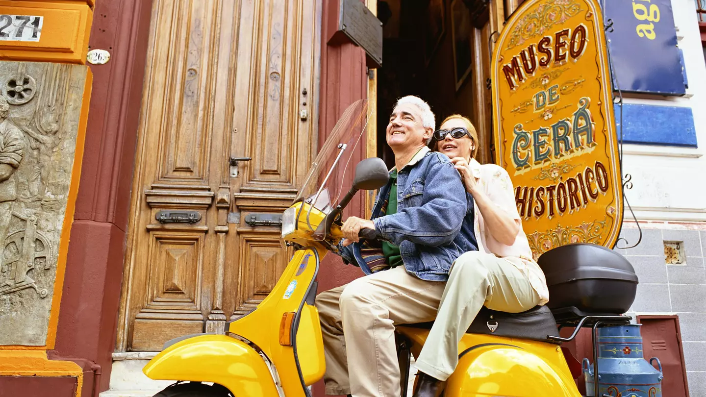 A couple sit on a scooter together outside the wax museum in Buenos Aires