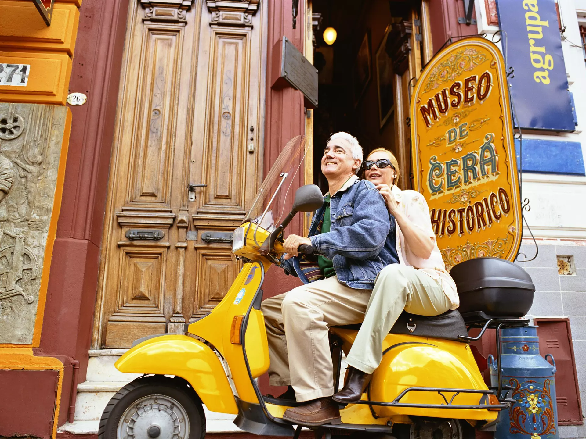 A couple sit on a scooter together outside the wax museum in Buenos Aires