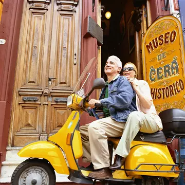 A couple sit on a scooter together outside the wax museum in Buenos Aires