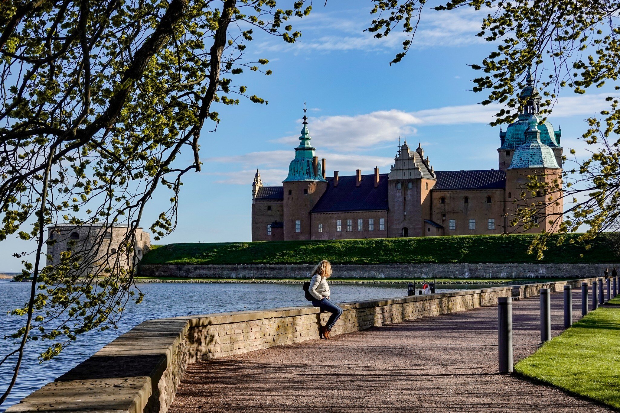 Kalmar, Sweden May 10, 2020 A woman sits on a wall on the grounds of the Kalmar Castle.; Shutterstock ID 1728247585; your: Sloane Tucker; gl: 65050; netsuite: Online Editorial; full: POI