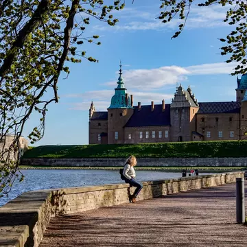 Kalmar, Sweden May 10, 2020 A woman sits on a wall on the grounds of the Kalmar Castle.; Shutterstock ID 1728247585; your: Sloane Tucker; gl: 65050; netsuite: Online Editorial; full: POI