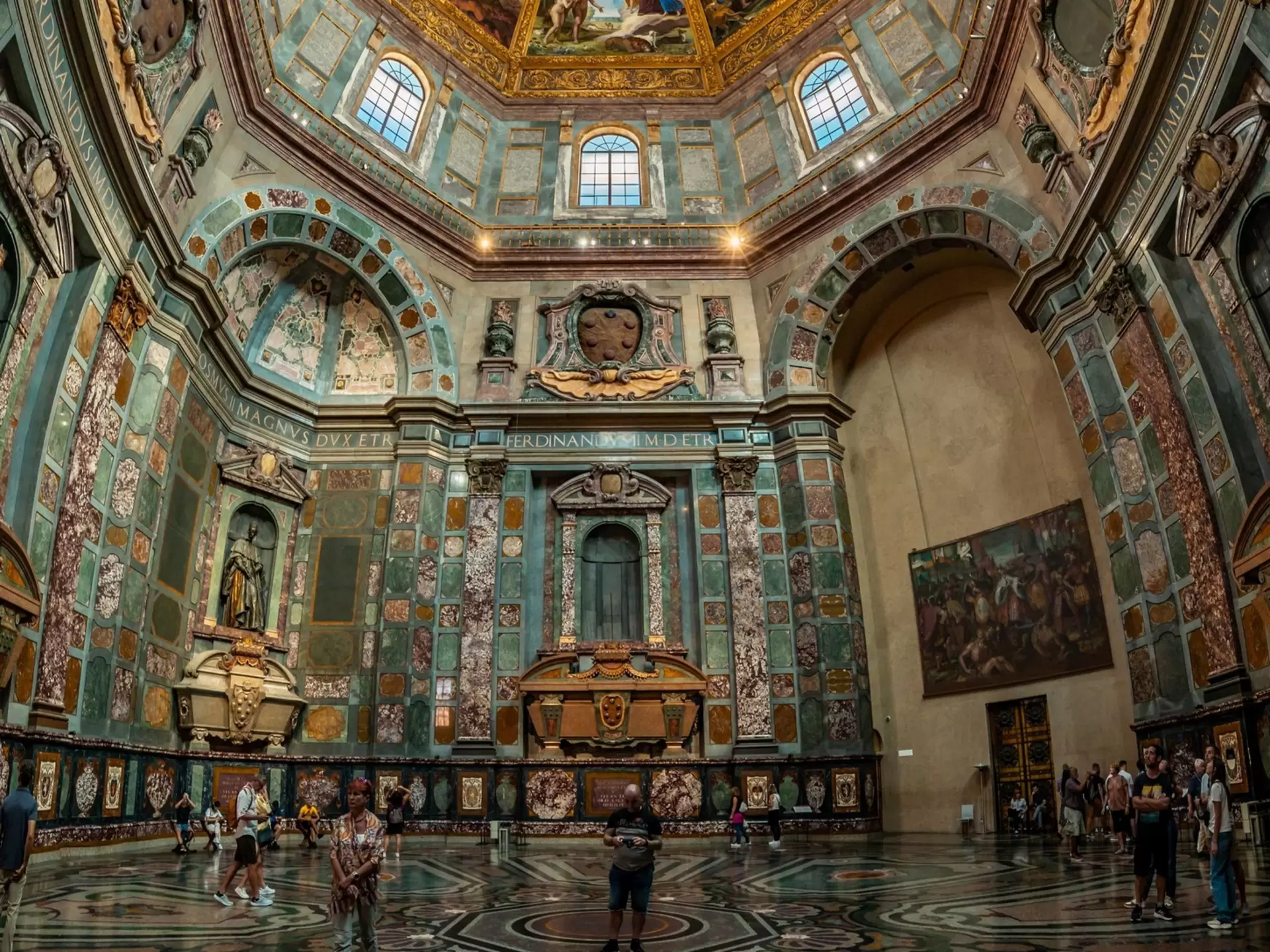 An intricate chapel with colorful tiles and art on the walls, including a painted dome ceiling