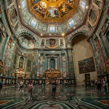 An intricate chapel with colorful tiles and art on the walls, including a painted dome ceiling