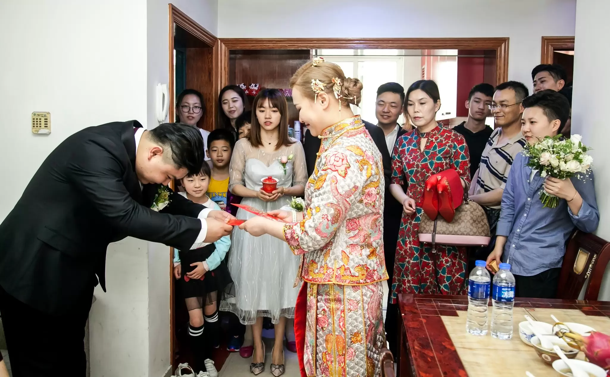 A Chinese groom giving his bride a red envelope from her mother-in-law. Jenson / Shutterstock
