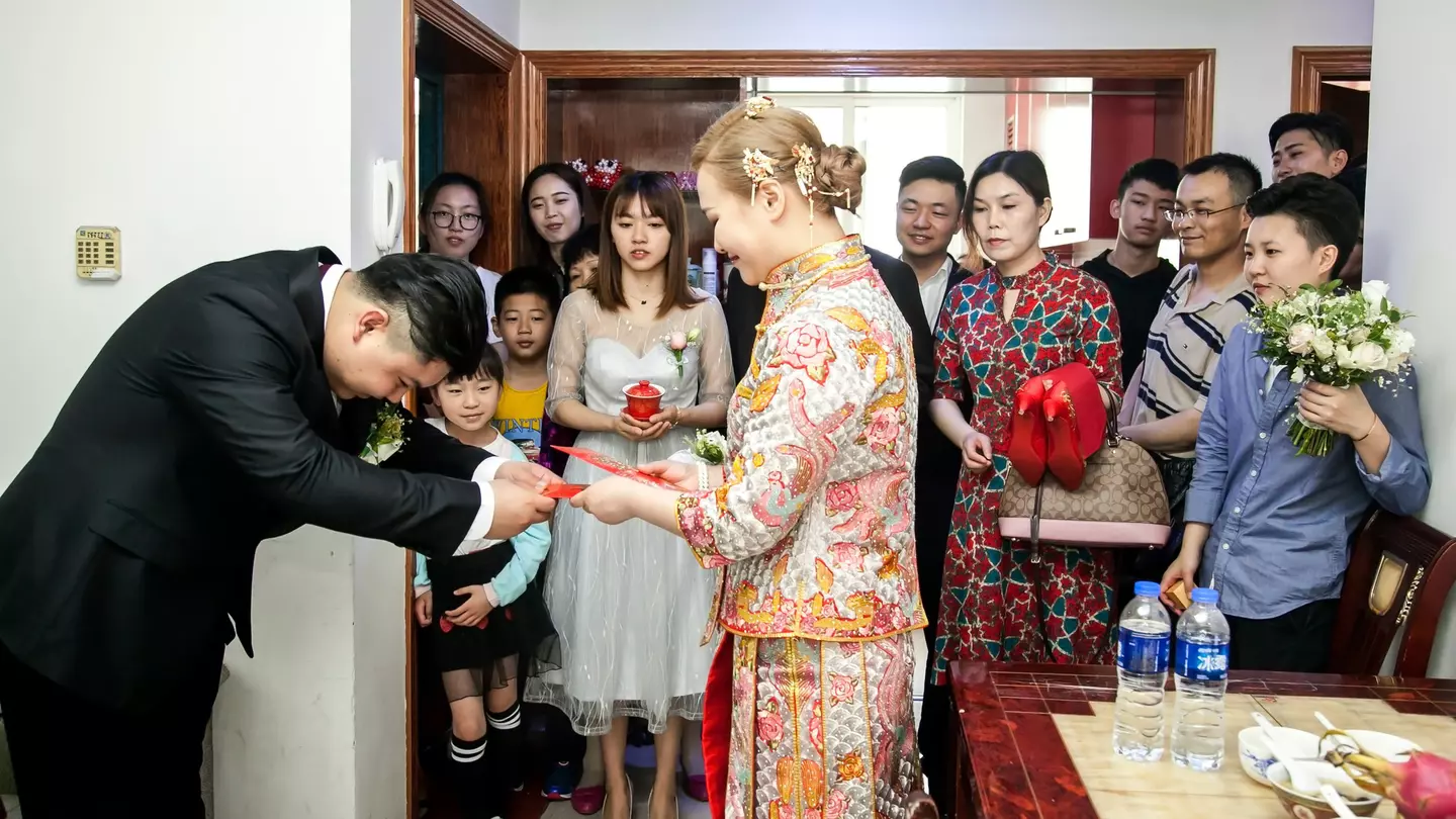 A Chinese groom giving his bride a red envelope from her mother-in-law. Jenson / Shutterstock