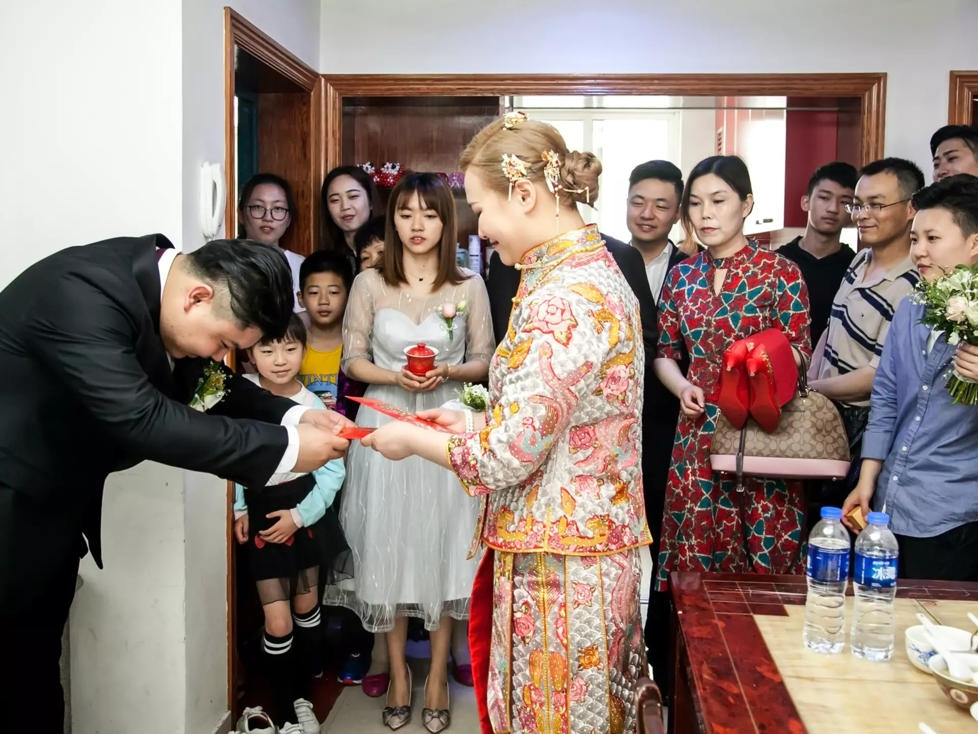 A Chinese groom giving his bride a red envelope from her mother-in-law. Jenson / Shutterstock