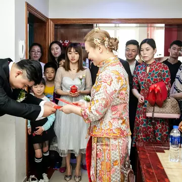 A Chinese groom giving his bride a red envelope from her mother-in-law. Jenson / Shutterstock