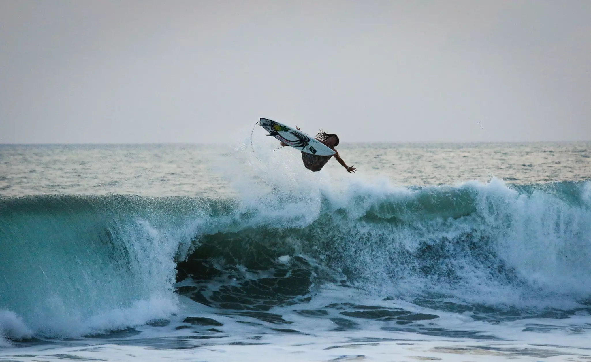 A surfer performs an aerial maneuver off the coast of El Tunco