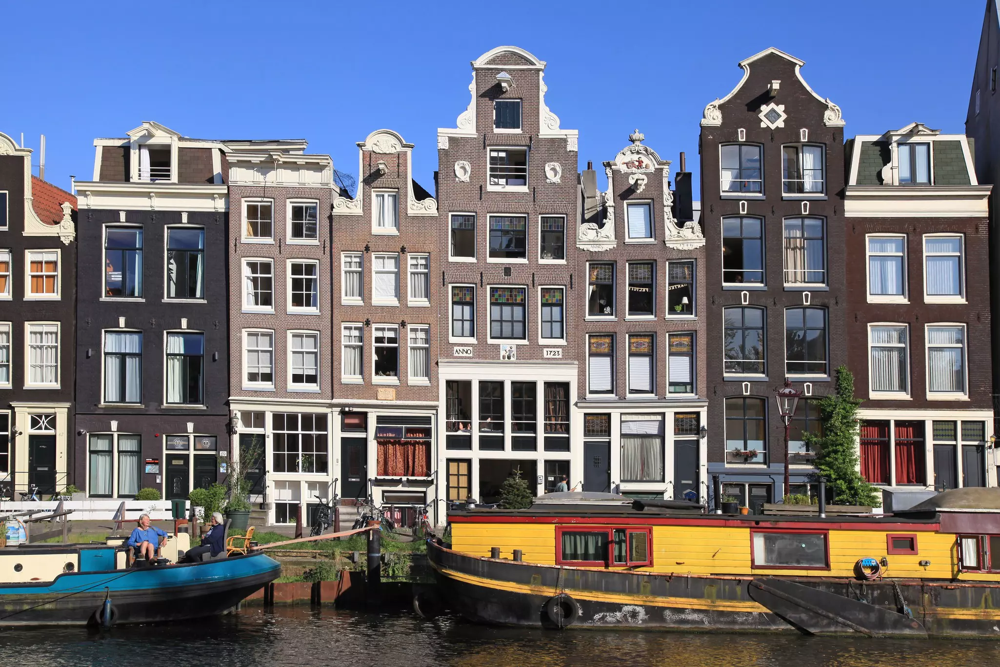 Traditional tall, narrow canal houses and houseboats in Amsterdam.