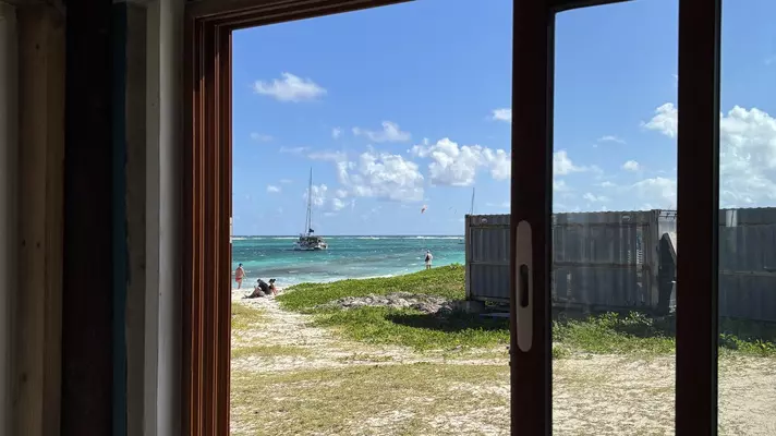 A beach and boat out at sea viewed through a window