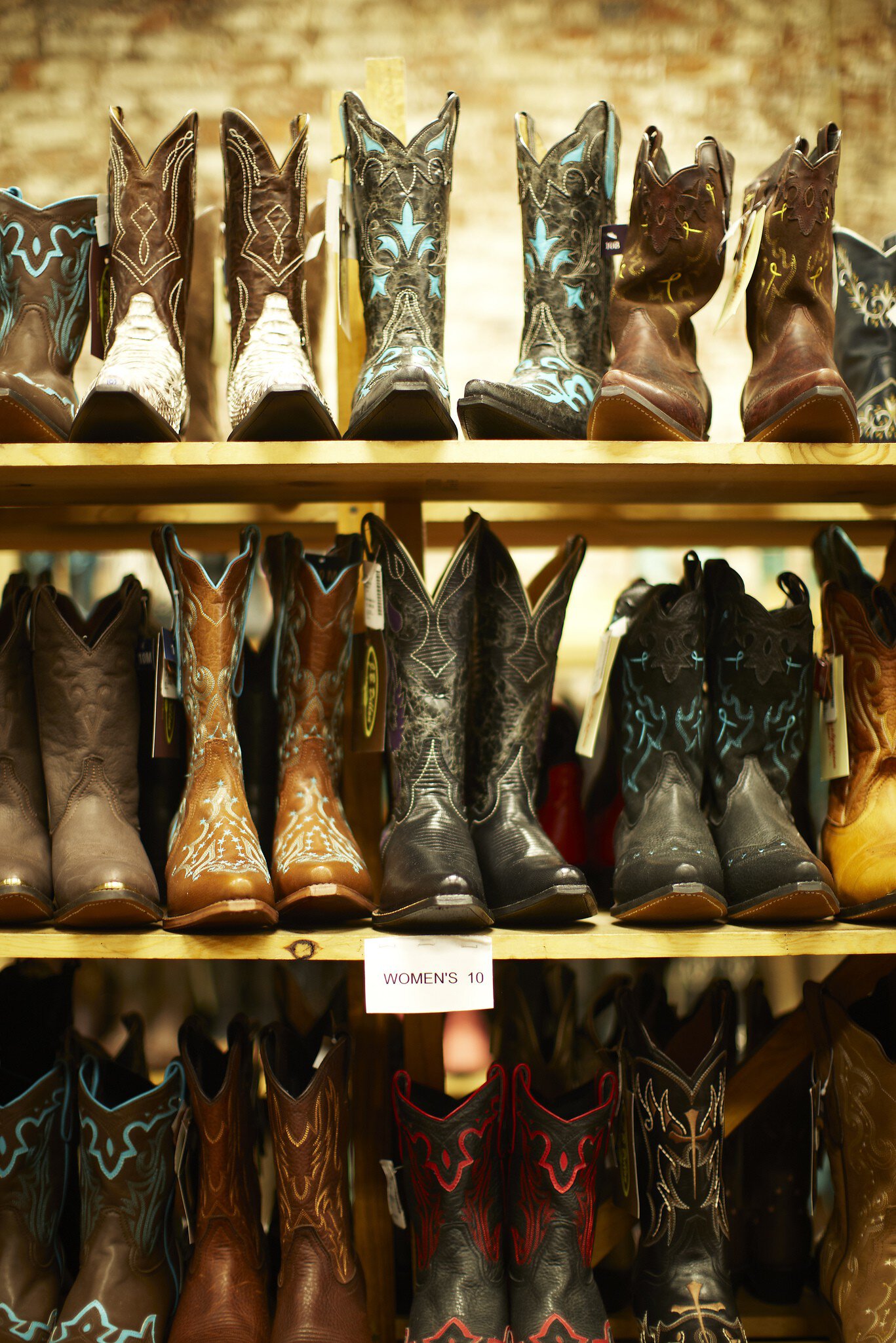 Cowboy boots standing in a row on a shelf in a store.
