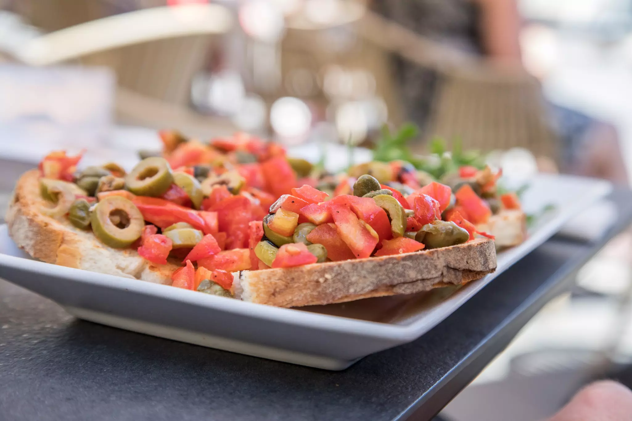 A plate with chopped tomatoes and olives on toasted bread