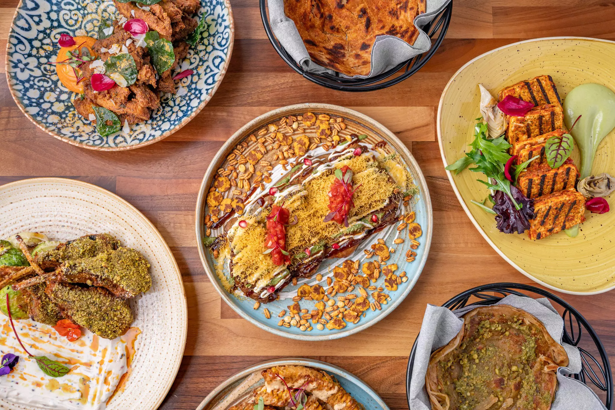Plates of food laid out on a table. Each dish is beatifully presented and decorated with garnish and sauce.