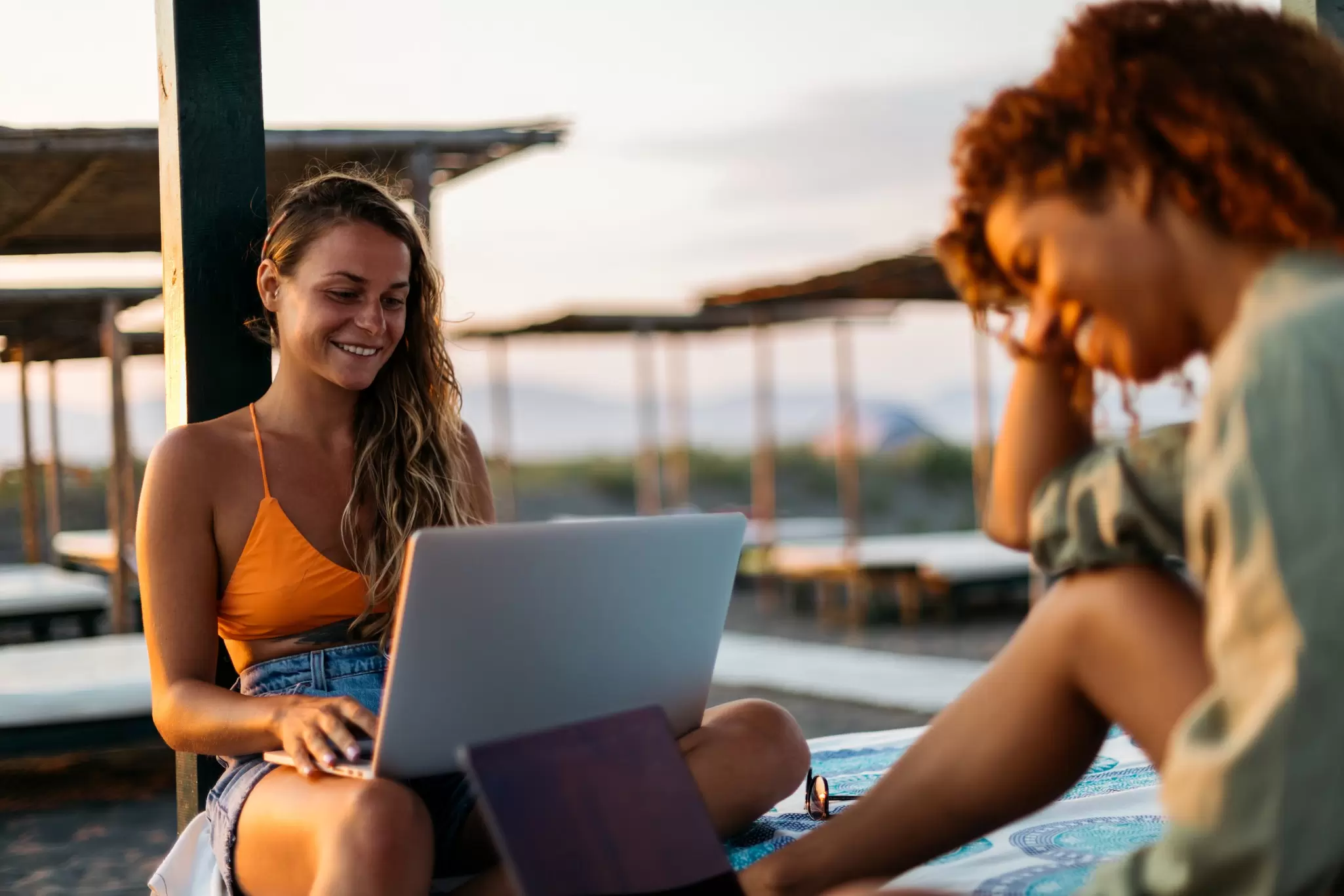 Young women working on laptops on a beach