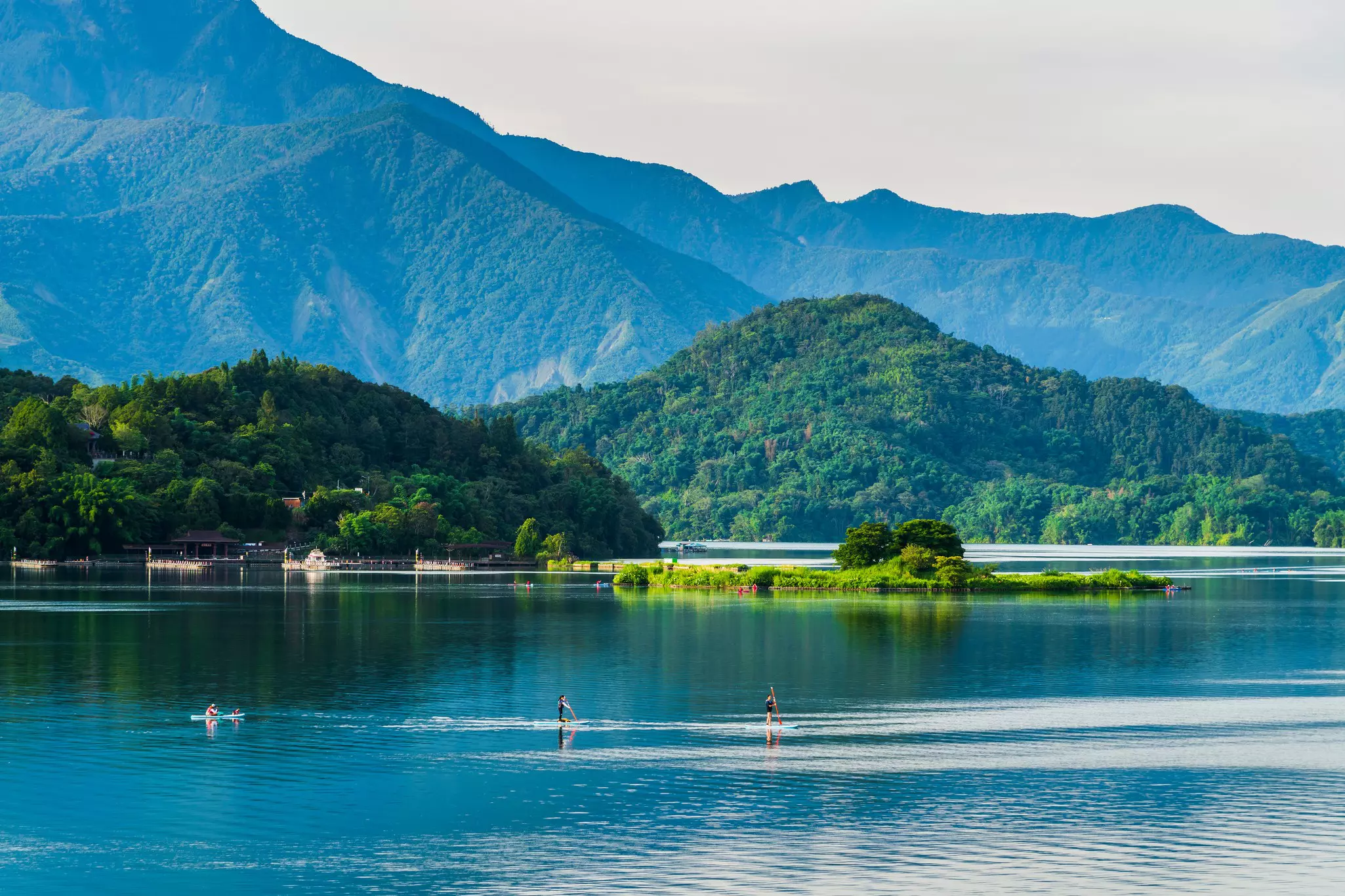 Paddleboarders on a lake surrounded by mountains and forests