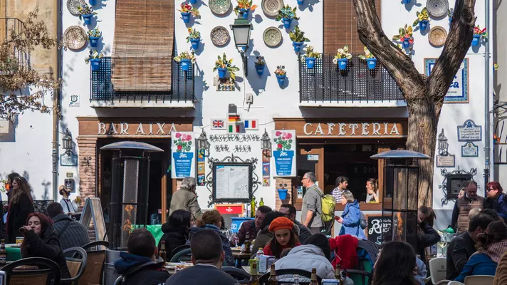 Bar Aixa Cafeteria storefront with decorative plates and local crafts adorning its white facade