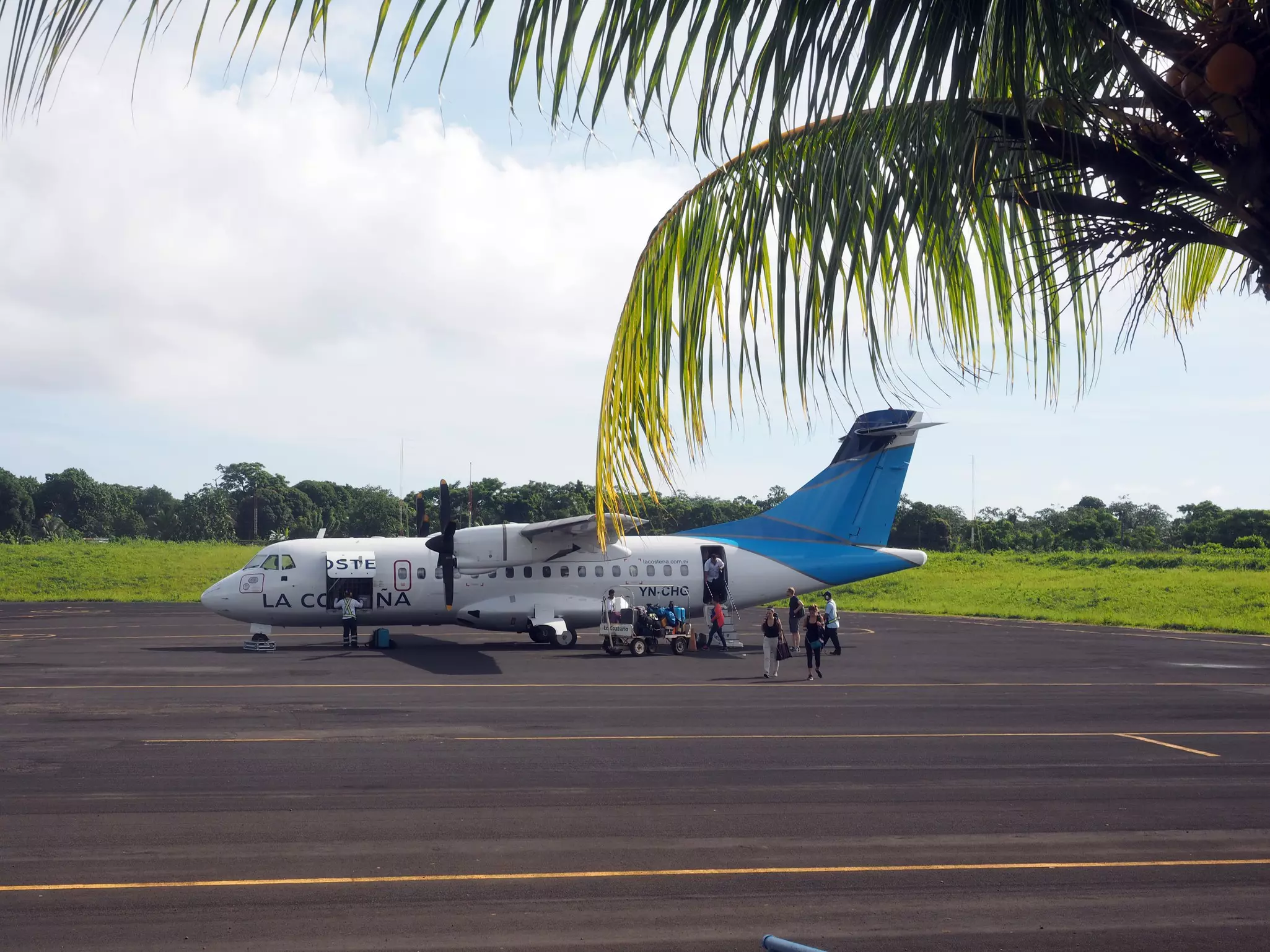 Tourists disembarking from twin prop plane on tarmac airport.