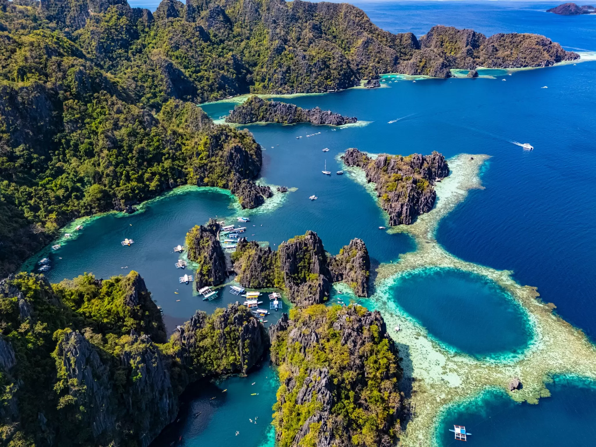 Two lagoons with boats and ferries moored in pockets of the coast. Philippines. 