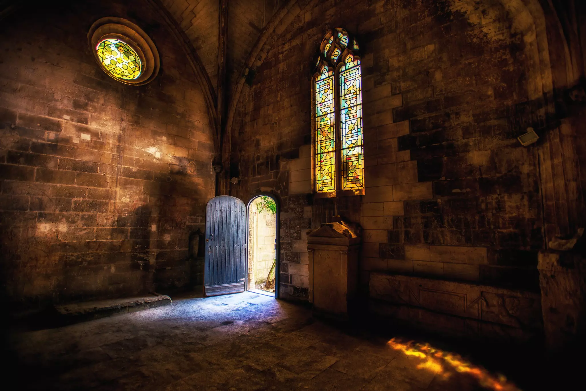 Sun streams through a stained-glass window in an abandoned church