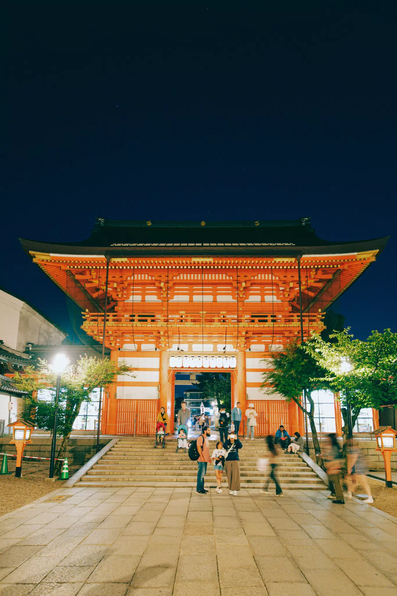 A family with two strollers bump their way down steps in front of a shrine.