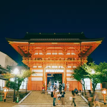 A family with two strollers bump their way down steps in front of a shrine.