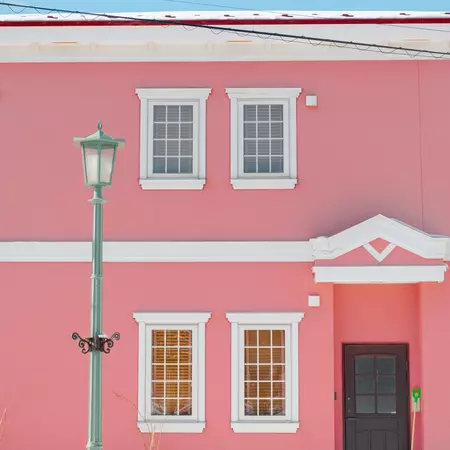 A close-up shot of the pink facade of a house, with white-painted details.