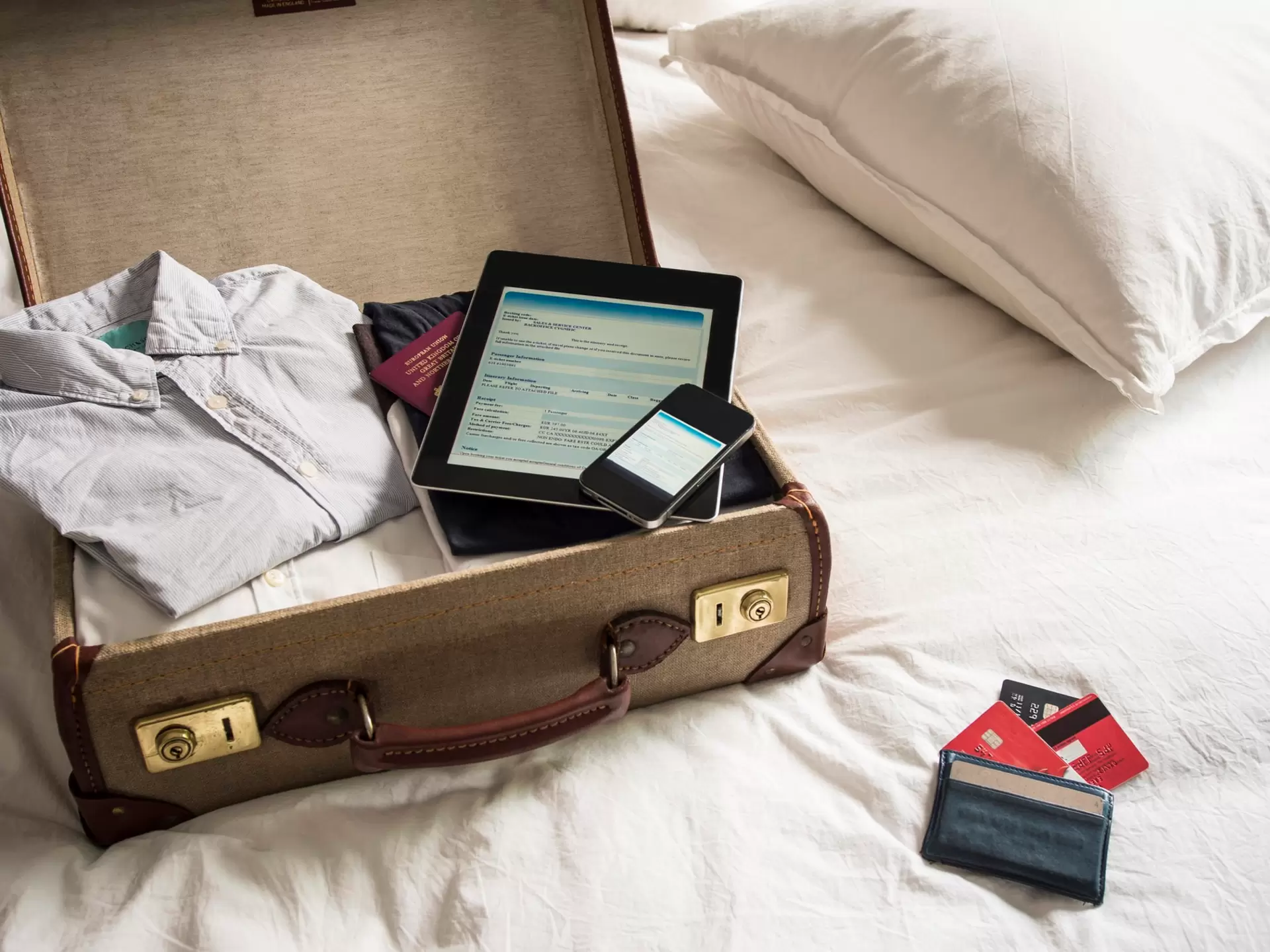 An open suitcase, with ipad, phone and passport inside