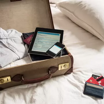 An open suitcase, with ipad, phone and passport inside