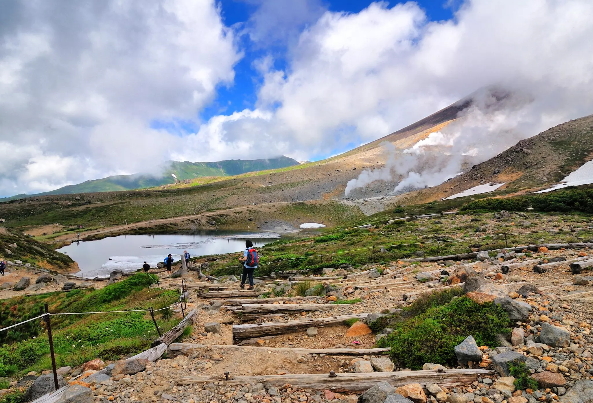Trekkers on a rope-lined trail on a mountain in an expansive park