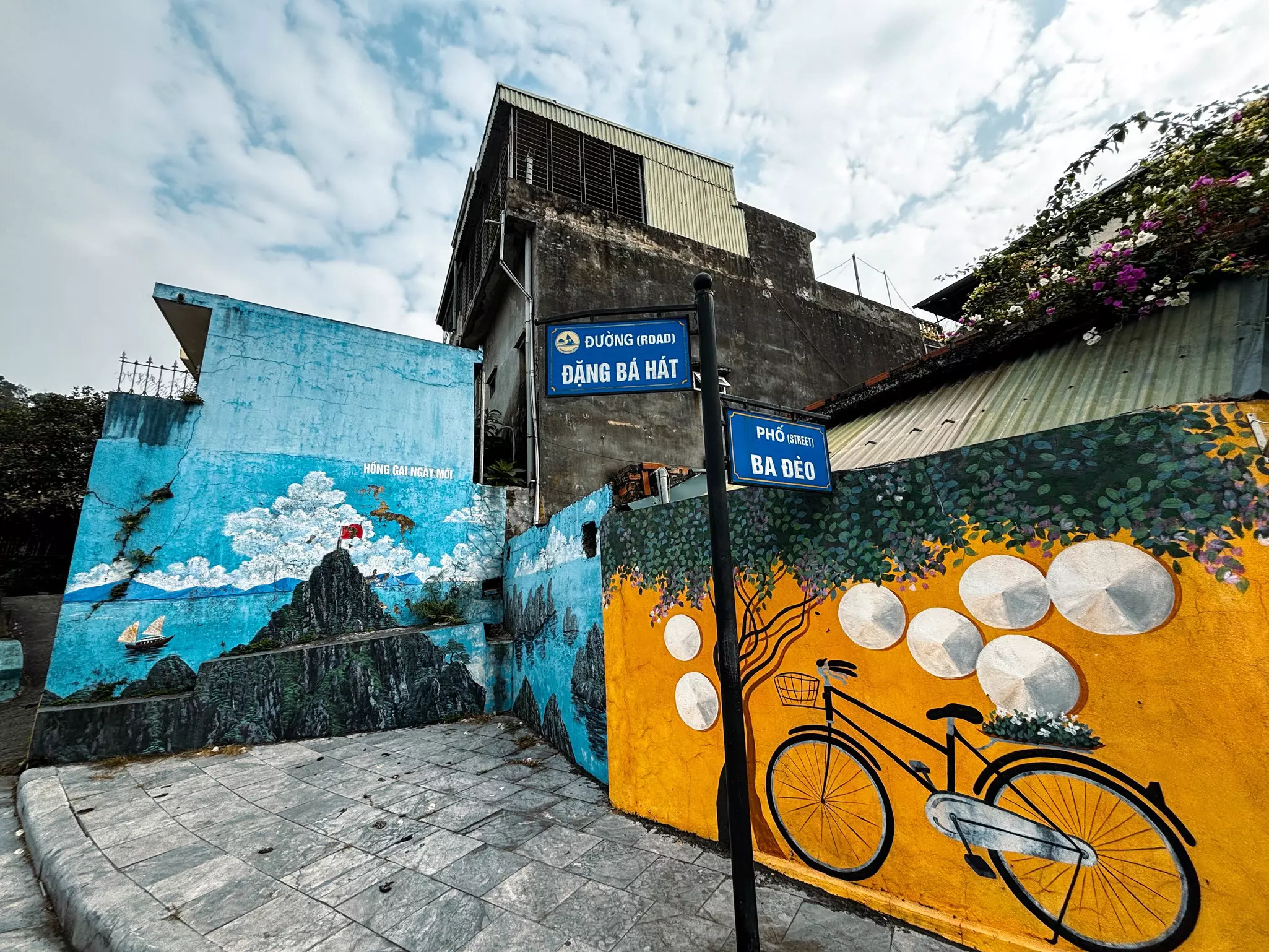 Murals of a cloudy Halong Bay and a bicycle topped by Vietnamese hats in Halong City, Vietnam.