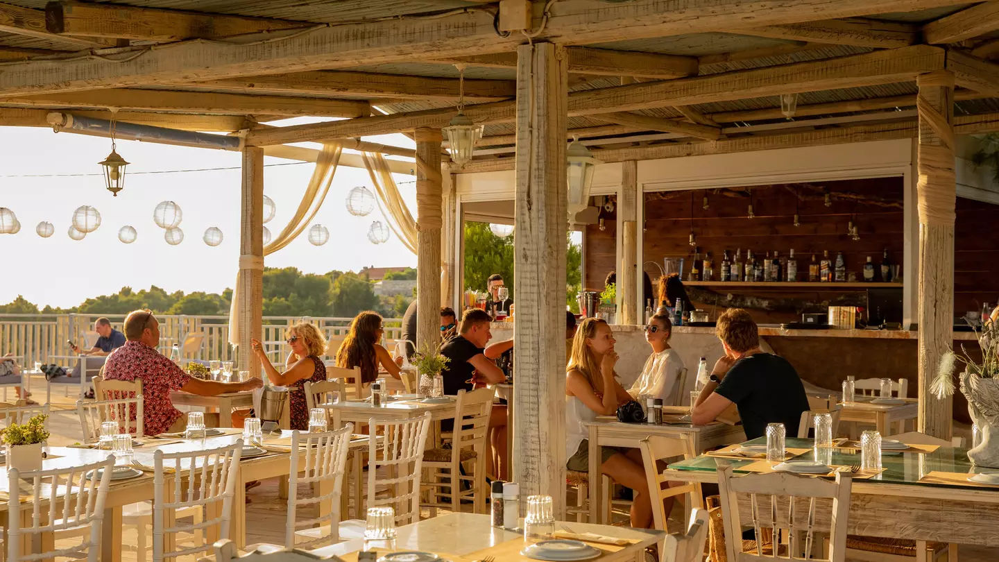 A restaurant terrace with diners at sunset.