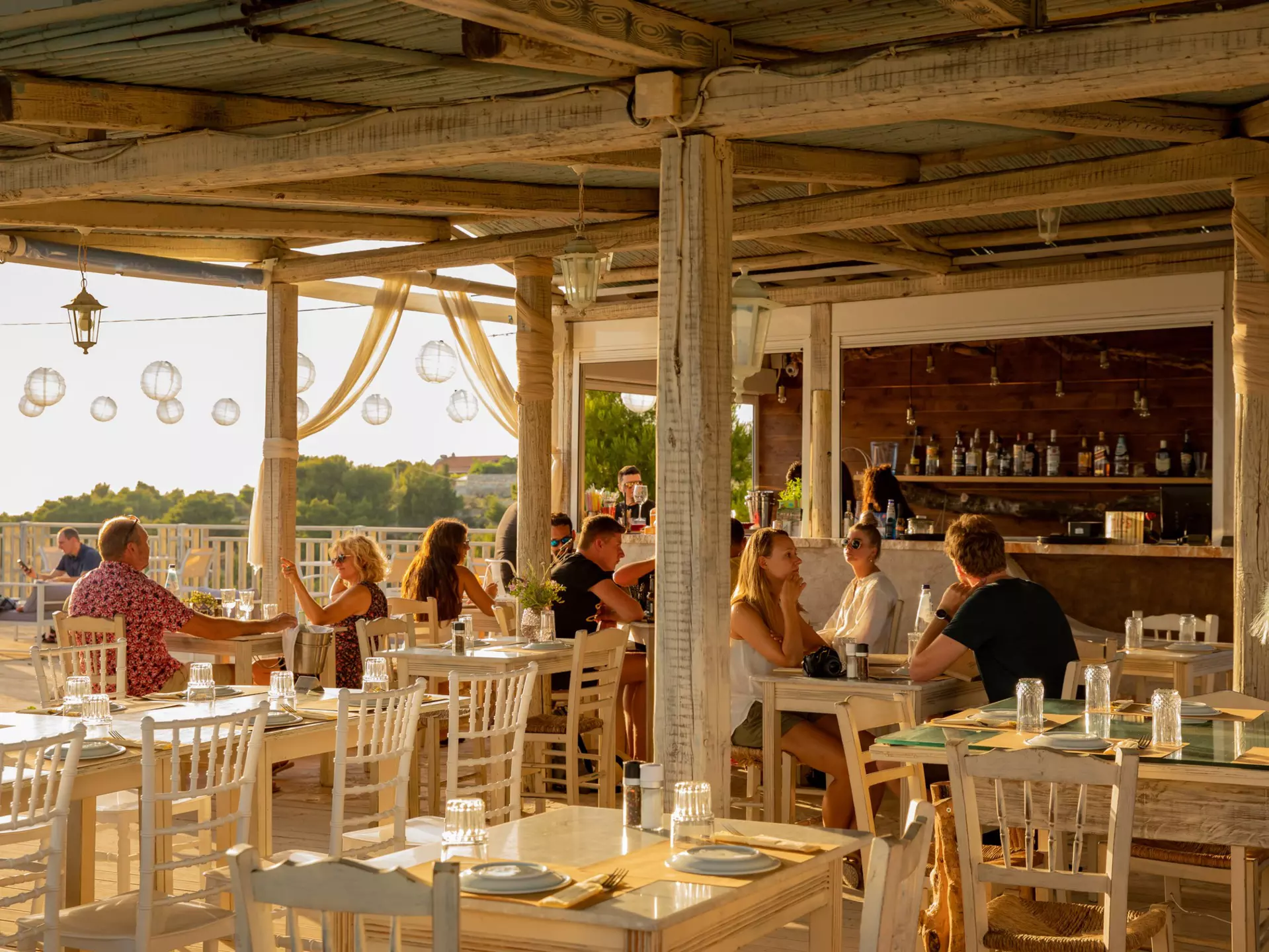 A restaurant terrace with diners at sunset.