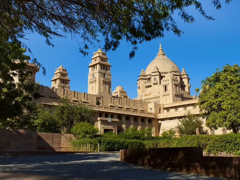 A tan palace with several towers and a dome in India.
