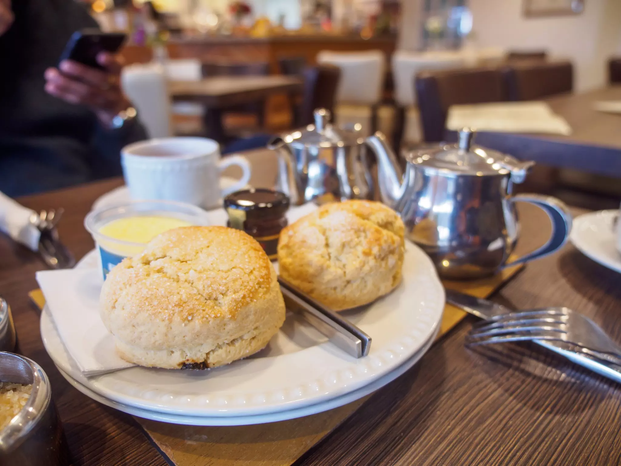 Wide closeup of freshly-baked scones with clotted cream and jam at a restaurant during afternoon tea. Tintagel, England. Travel and Cornish cuisine.