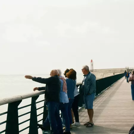 Sightseeing in la Chaume, Les Sables d'Olonne, Vendée, France - tourists on the grande jetée with a lighthouse in the background