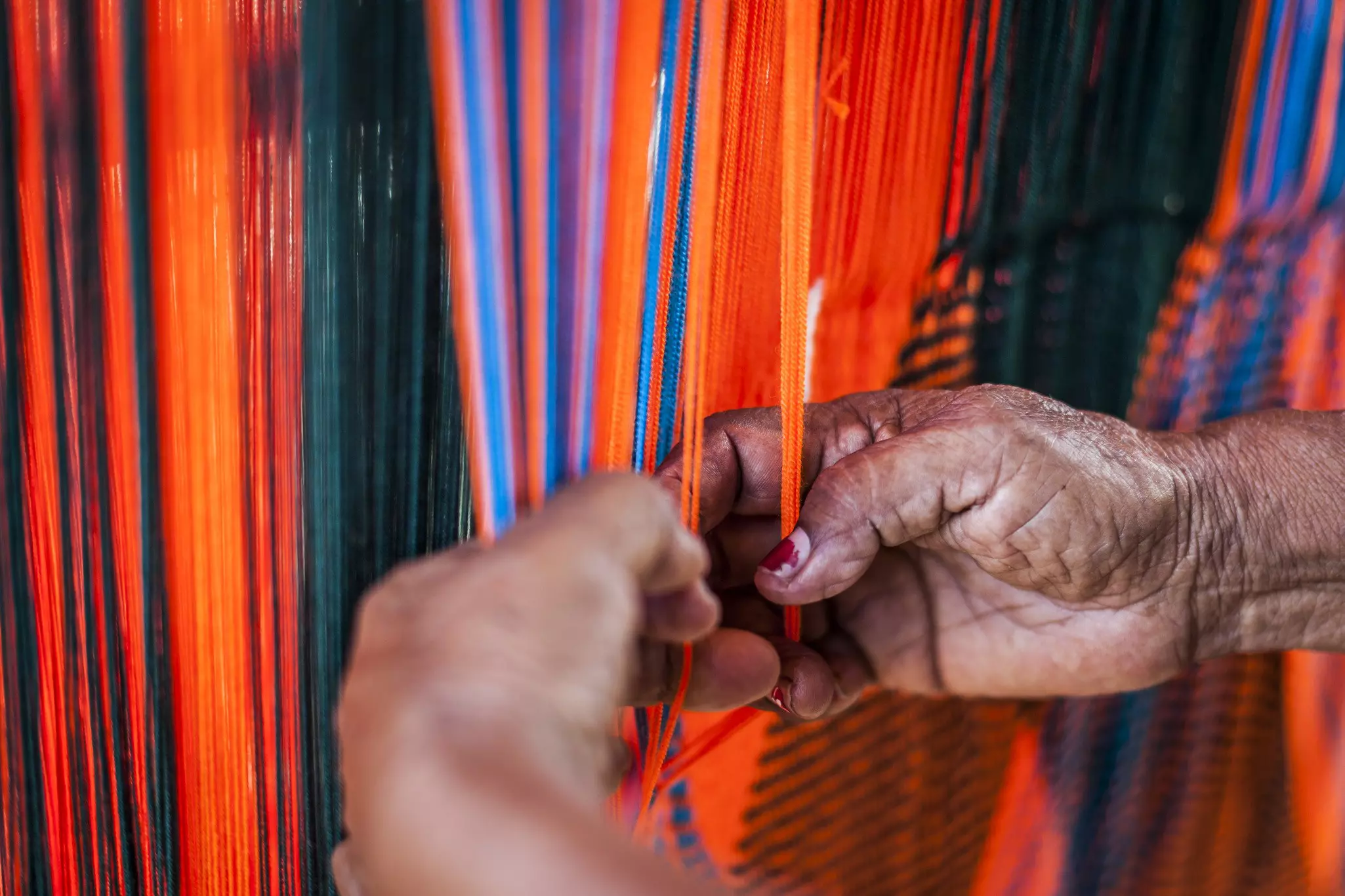 Close-up of a womans hands weaving a chinchorro (Colombian hammock) in the town of Uribia.