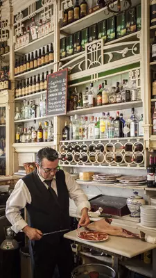 A hand holds out a dish serving spinach and chickpea stew topped with two croutons