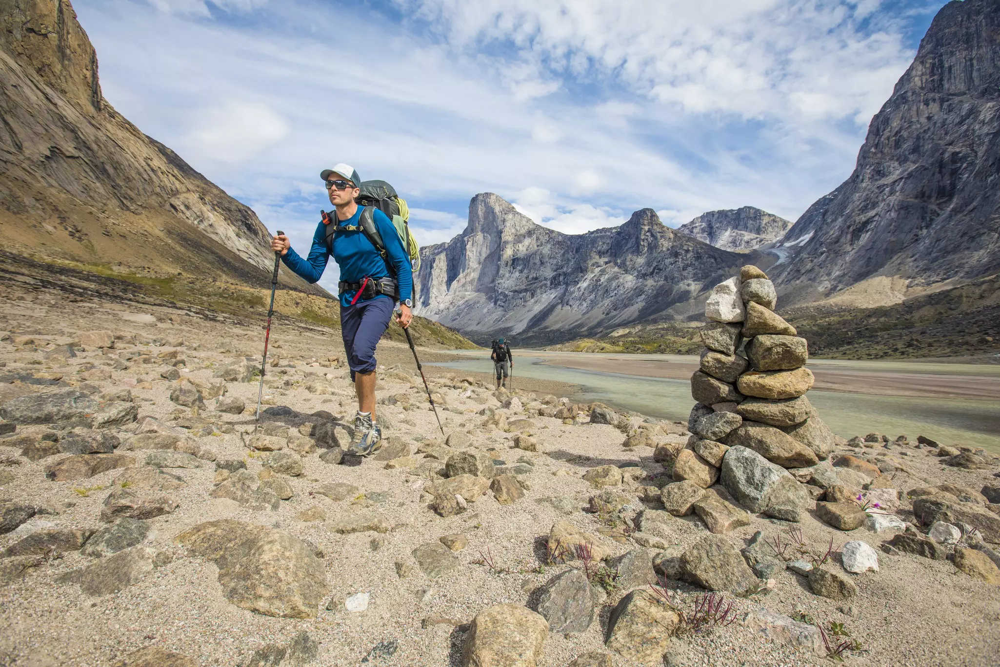 A hiker passing rock cairns on the hike to the Akshayunk Pass in Auyuittuq National Park.