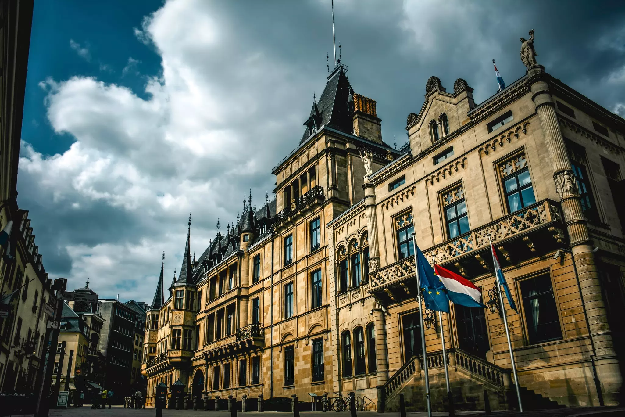 The facade of a palace in a city is seen in dramatic light.