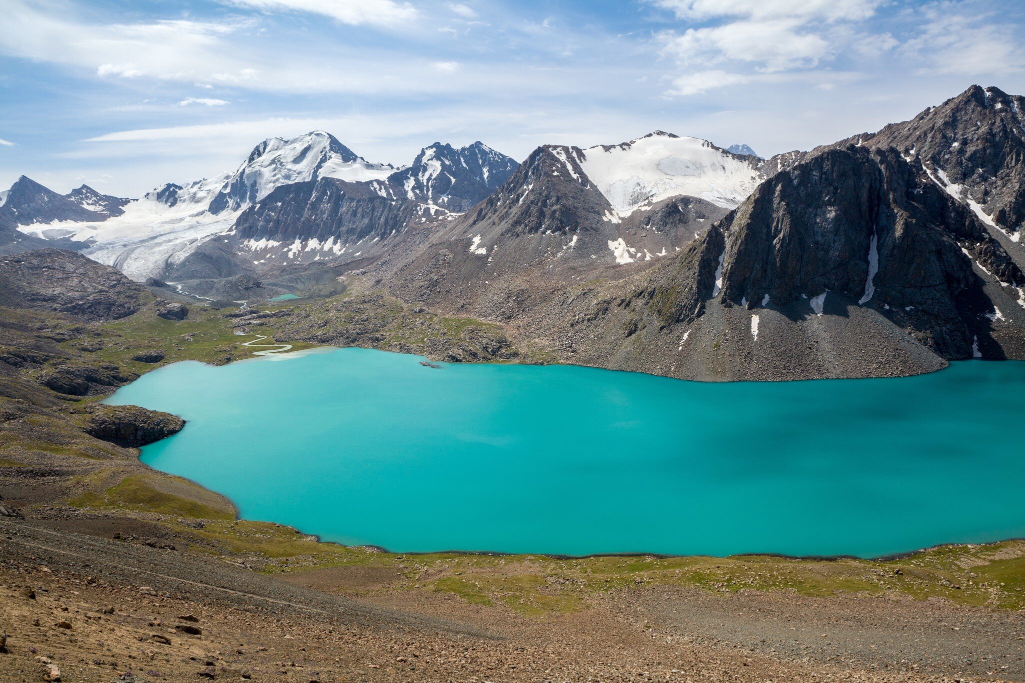 A turquoise lake (Ala-Kul) and snow-capped mountains in Kyrgyzstan.