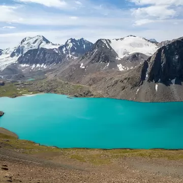 A turquoise lake (Ala-Kul) and snow-capped mountains in Kyrgyzstan.
