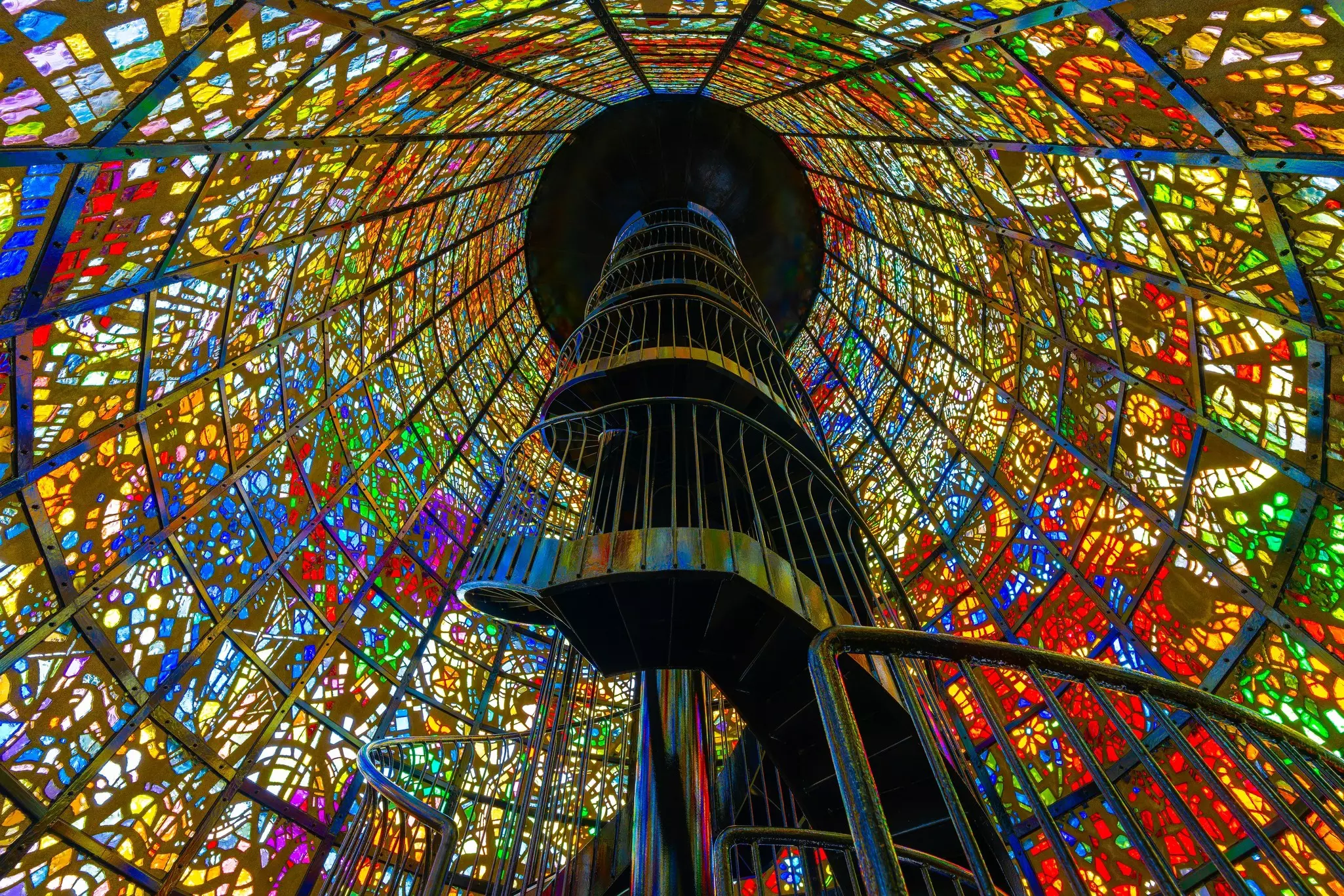 A spiral staircase within a stained glass art installation.