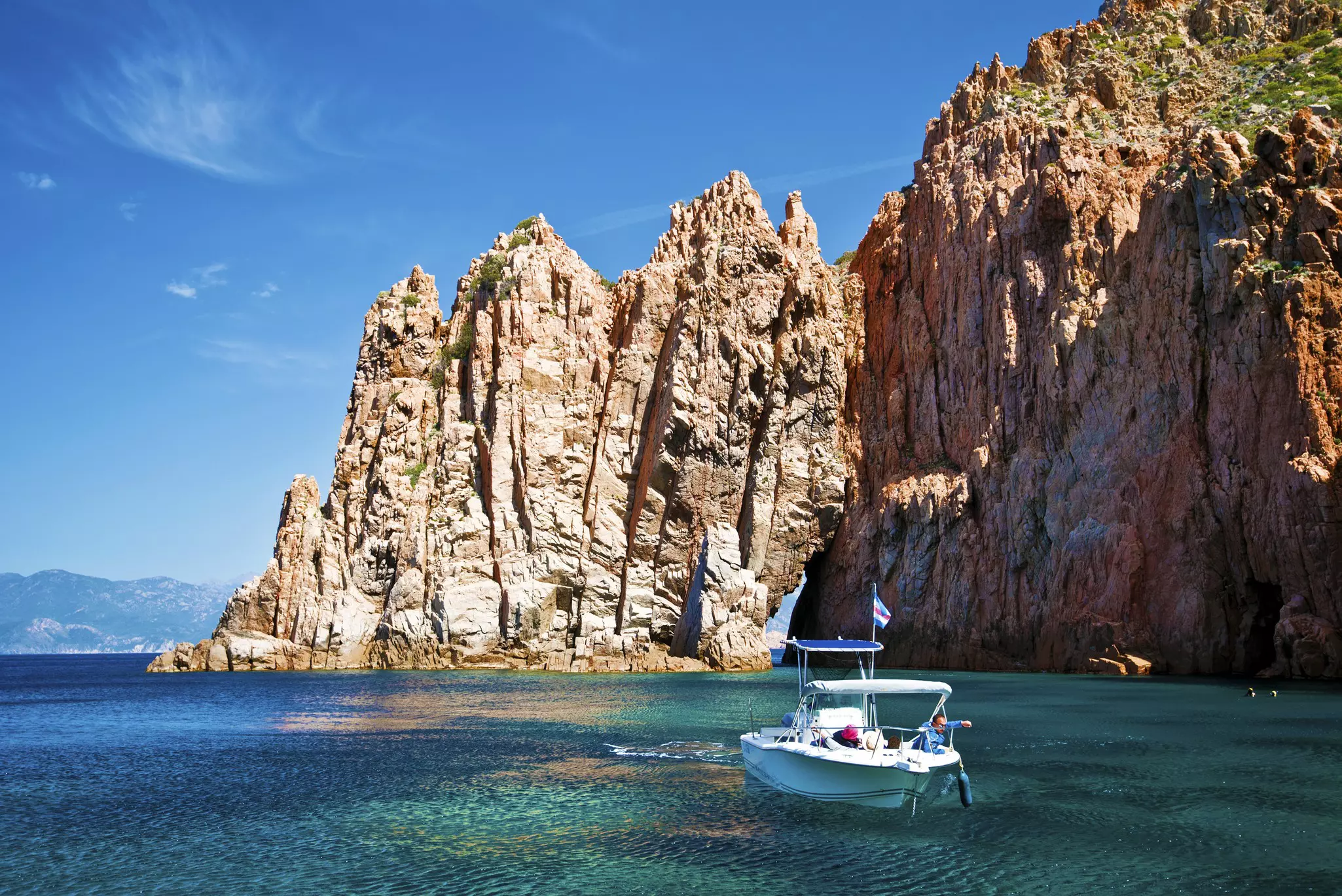 The tourist boat is nearby the Capo Rosso rocks of Calanques de Piana. Western coastline of Corsica island, Corse-du-Sud, France  